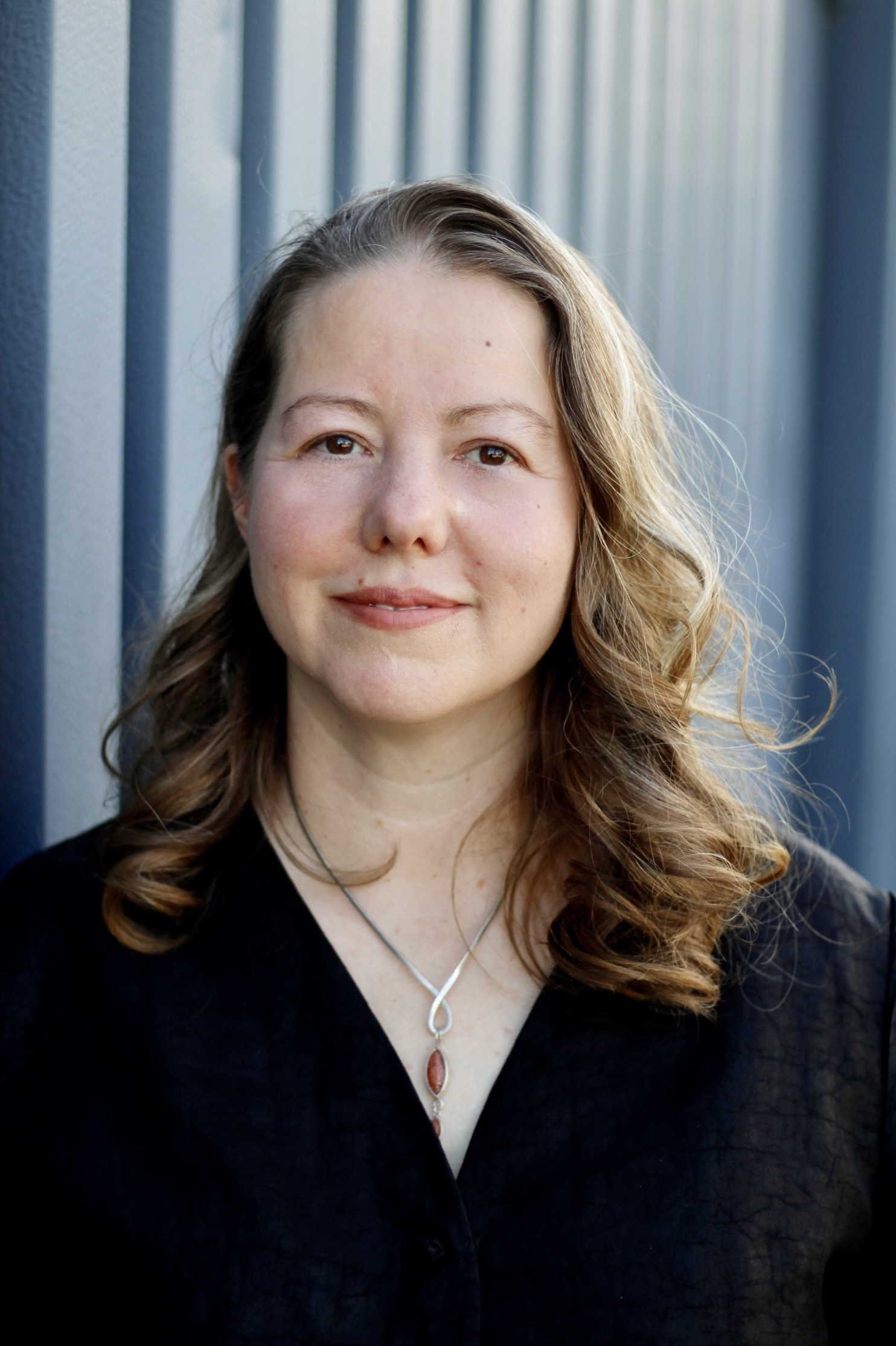 Portrait von Daniela Grebe vor einem blaugrauen Hintergrund
